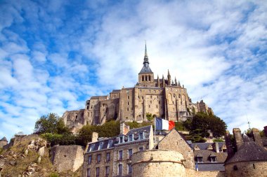Güzel Abbey, Mont San Michel'in gün güneşli yaz. Gelişen Fransız bayrağı. Mavi gökyüzü ile beyaz bulutlar. Normandy. Fransa.