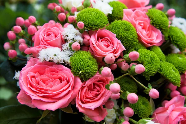 Beautiful bouquet with pink roses and small small flowers. Green ornamental plants in the bouquet. Festive bouquet for wedding and birthday