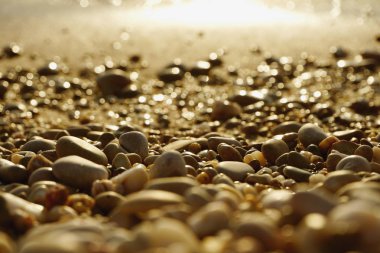 Arka plan ve ön plan günbatımı sarı beyaz ile Karadeniz kıyısında deniz çakıl bulanık. 