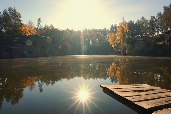 Коростышевский карьер, Украина. Яркое солнце над лесом отражается в озере — стоковое фото