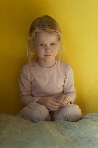Portret van een klein beledigd meisje. Ontevreden meisje op een achtergrond van gele muur — Stockfoto
