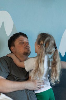  Baba küçük kızına sarılıyor. Kızı babasına yapıştı.