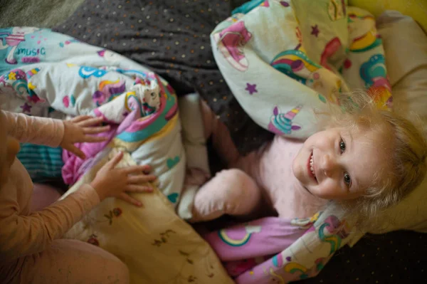 Twee zussen spelen met een typemachine op het bed — Stockfoto