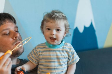  Babam evde çocuklarıyla sabun köpüğü oynuyor. Babam evde üç çocukla oynuyor: bir oğlan ve kızlar, erkek ve kız kardeşler.