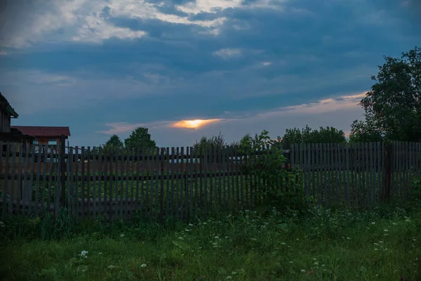 Wiejski zachód słońca. Zachód słońca w wiosce. Drewniane ogrodzenie przy zachodzie słońca — Zdjęcie stockowe