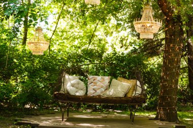 metal kanepe ormanın içinde. Kristal avizeler asılı  