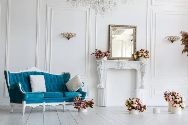 Classic blue sofa in luxurious white room. artificial fireplace