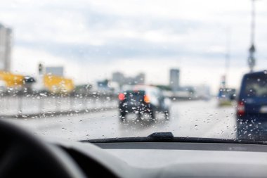 Su damlaları ön cam, trafikte şehir yağmurlu günde, Araba ön cam görünümü, üzerinde koyu arka plan bulanık.. 