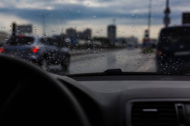 Su damlaları ön cam, trafikte şehir yağmurlu günde, Araba ön cam görünümü, üzerinde koyu arka plan bulanık.. 