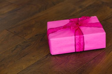 Ahşap arka planda kurdeleli pembe hediye kutusu 