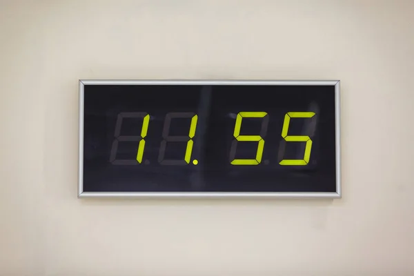 Black digital clock on a white background showing time eleven hours 55 minutes