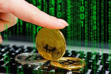Golden bitcoin in fingers with the laptop keyboard background crypto currency concept  clipart