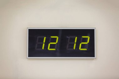 Saat on iki saat on iki dakika gösterilen beyaz bir arka plan üzerinde siyah dijital saat