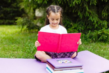 Kitap, yaz yeşil Parkı'nda oturan okuma küçük şirin kız portresi.