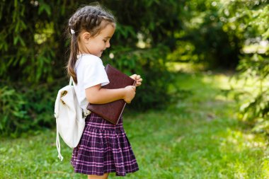 Orman yaz park arka plan üzerinde kitapla, sevimli küçük kız