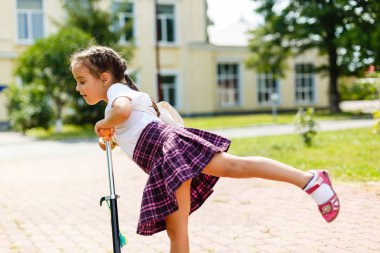 Çocuk okula geri binme motorla. Küçük kız açık havada tekme tahtada dengelemek öğrenme oynamaya. Çocuklar banliyölerinde scooter sokak sürmek.