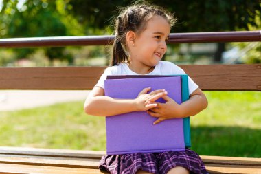 küçük bir kızın elinde renkli kitaplar