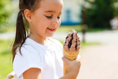 Güzel küçük kız yazın dondurma yiyor.