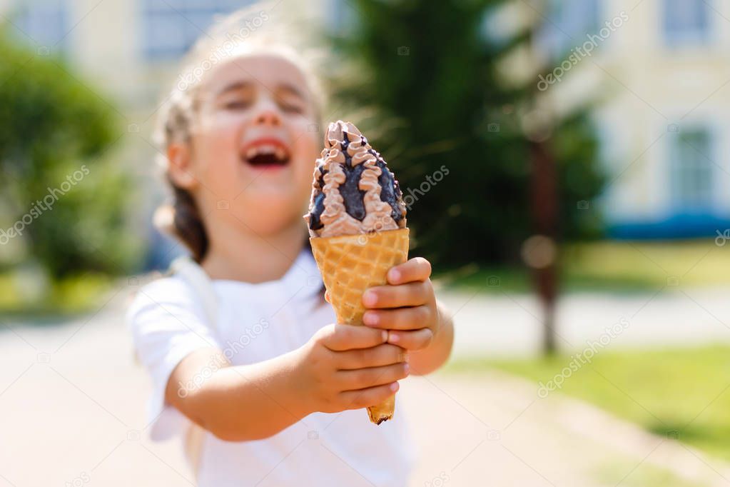 Cute little girl eating ice cream cone on the street