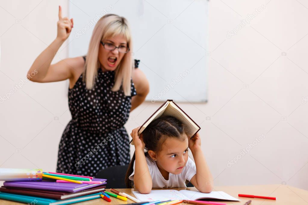angry teacher screaming at little schoolgirl in classroom