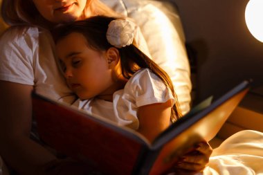 yatağa yatmadan önce kitap Genç Anne ve küçük kız okuma