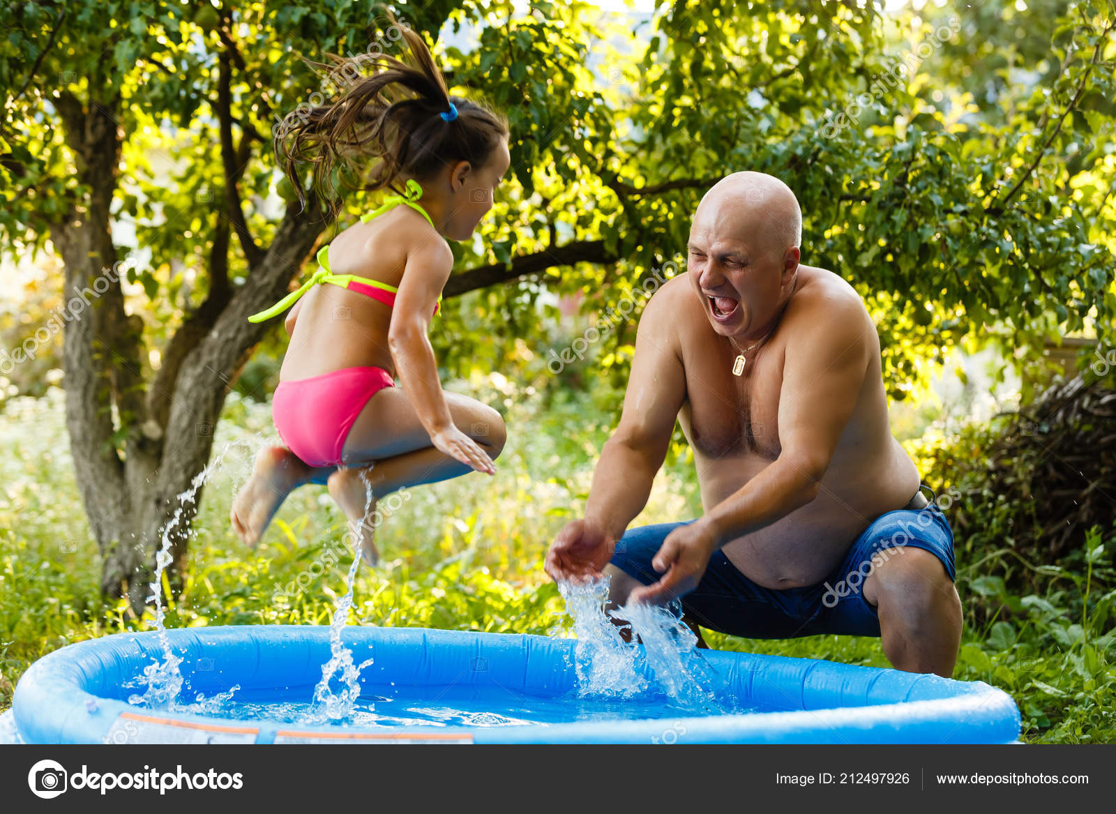Grand Père Avec Petite Fille Jouant Dans Une Piscine Gonflable