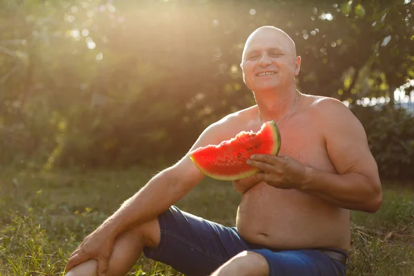 old gray-haired man eating watermelon. hot summer day. July