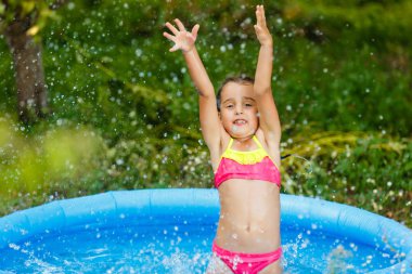 Küçük kız yeşil bahçesinde şişme havuzda eğleniyor 