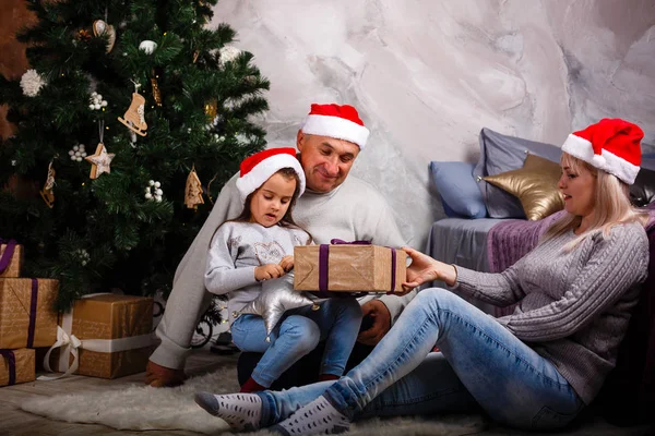 母と祖父の家でクリスマス ツリーのそばに座って楽しんで少女 — ストック写真
