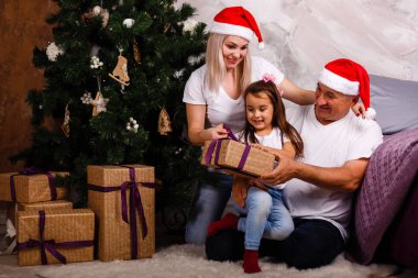 Noel ağacı yakınındaki kızı ve torunu ile vakit Santa şapkalı yaşlı adam