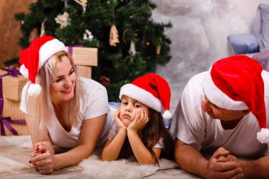 Noel ağacı yakınındaki kızı ve torunu ile vakit Santa şapkalı yaşlı adam