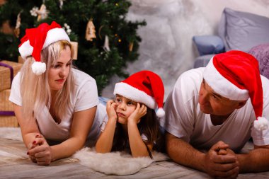 Noel ağacı yakınındaki kızı ve torunu ile vakit Santa şapkalı yaşlı adam