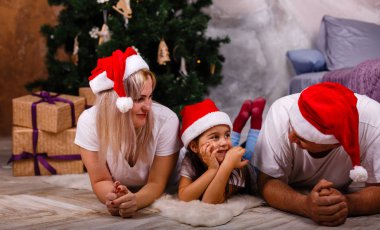 Noel ağacı yakınındaki kızı ve torunu ile vakit Santa şapkalı yaşlı adam