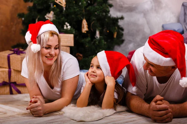 Noel ağacı yakınındaki kızı ve torunu ile vakit Santa şapkalı yaşlı adam