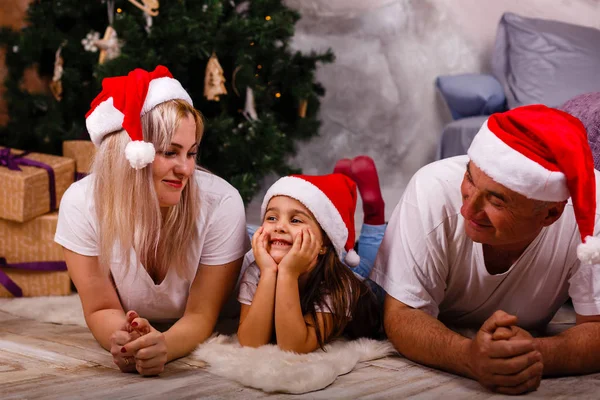 Noel ağacı yakınındaki kızı ve torunu ile vakit Santa şapkalı yaşlı adam