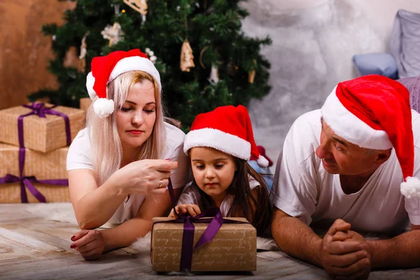 Noel ağacı yakınındaki kızı ve torunu ile vakit Santa şapkalı yaşlı adam