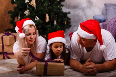 Noel ağacı yakınındaki kızı ve torunu ile vakit Santa şapkalı yaşlı adam