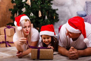 Noel ağacı yakınındaki kızı ve torunu ile vakit Santa şapkalı yaşlı adam