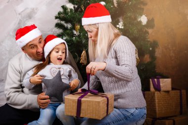 Noel ağacı yakınındaki kızı ve torunu ile vakit Santa şapkalı yaşlı adam