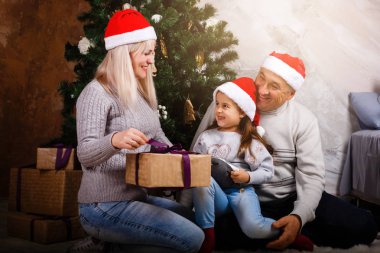 Noel ağacı yakınındaki kızı ve torunu ile vakit Santa şapkalı yaşlı adam