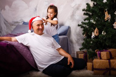 Yaşlı adam onun torunu Noel ağacı yakınındaki oynamaktan Santa şapka resmi