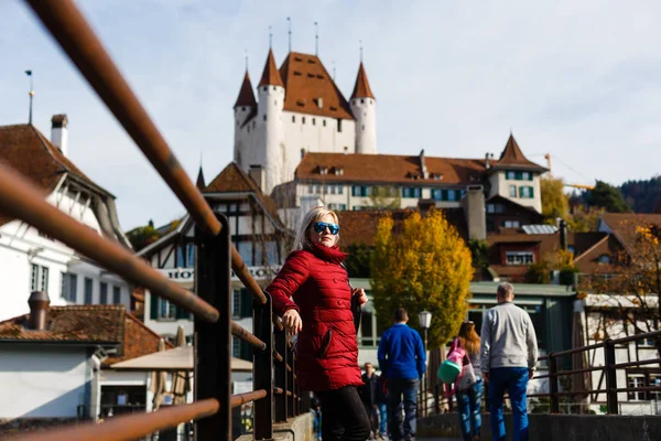 Adult woman walking on old bridge with ancient castle on background