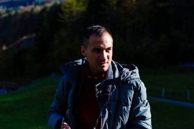 Güneşli bir günde siyah ceketli ve eşarplı yakışıklı bir adamın portresi.