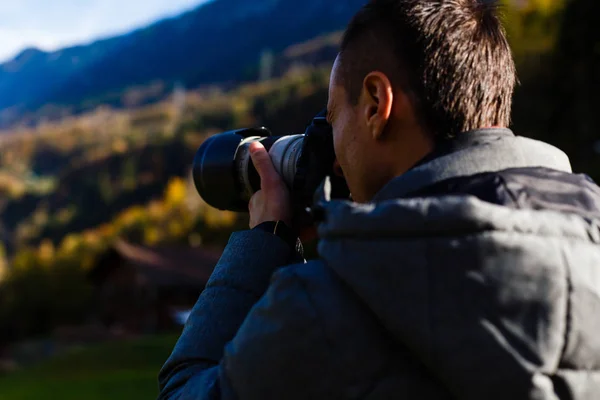 Nature photographer tourist with camera shoots while standing of the mountain.