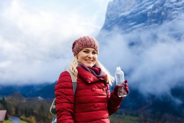 Sırt çantalı genç bir kadın dağın tepesinde duruyor. 