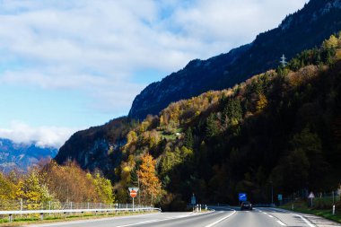 Güzel boş dağ yol, asfalt yol, yüksek kayalar, ağaçlar ve güneşli gökyüzü manzara. Vintage tonlama. 