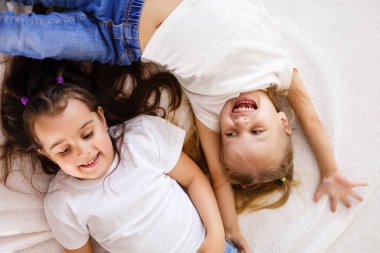 Beyaz yatakta yatarken iki mutlu küçük kız kardeş ana sayfa görünümü