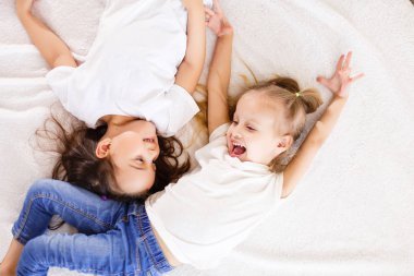 Beyaz yatakta yatarken iki mutlu küçük kız kardeş ana sayfa görünümü