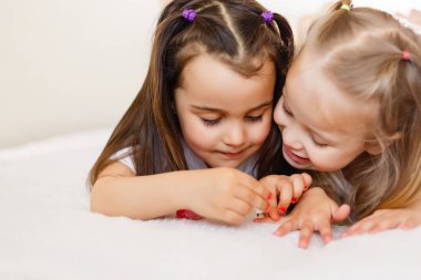 Two little girls painted their nails at home. clipart