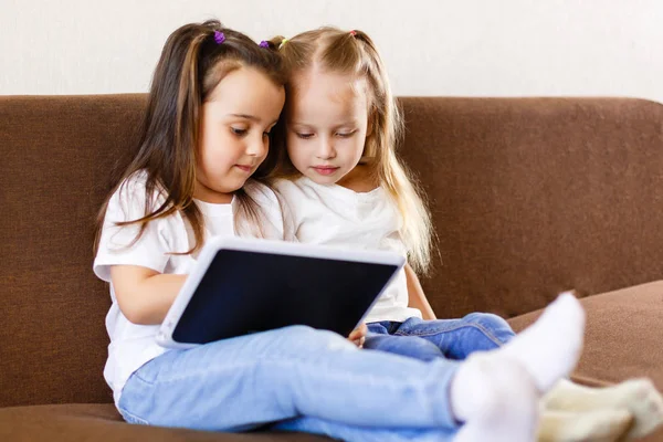 Dos Adorables Hermanitas Jugando Con Tableta Digital Sentadas Sofá Casa —  Fotos de Stock